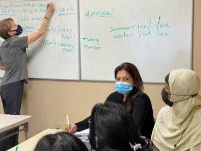 Teacher writing on white board at DeNeuville Learning Center for Women